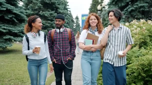 Vrolijke studenten multi-etnische groep wandelen buitenshuis in campus praten — Stockvideo