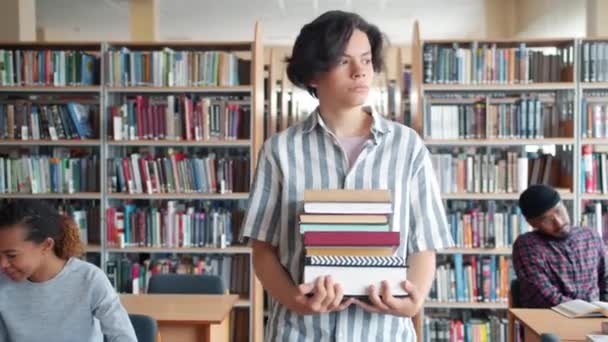 Hübsche junge Studentin läuft in College-Bibliothek und hält Bücher in den Händen — Stockvideo