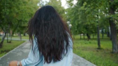 Parkta yürüyen güzel Asyalı bayanın arka dansı kameraya dönerek gülümseyerek