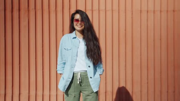 Mujer asiática joven de pie al aire libre con ropa de moda y gafas de sol — Vídeos de Stock