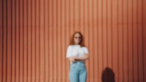 Retrato zoom de chica pelirroja en gafas de sol al aire libre cerca de la pared — Vídeo de stock