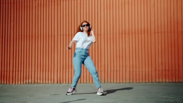 Movimento lento de adolescente feliz em fones de ouvido dançando cantando ao ar livre na cidade — Vídeo de Stock