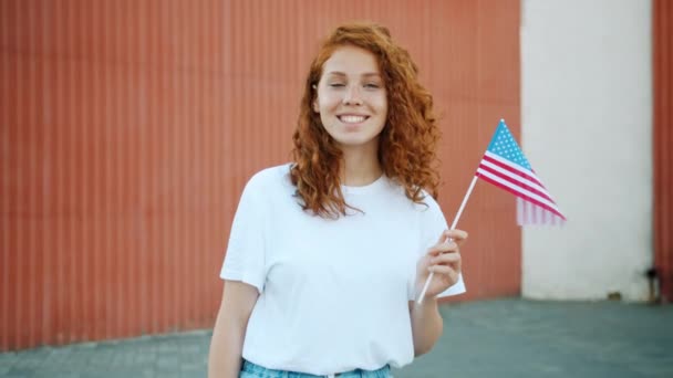 십대 소녀 애국자 들고 우리 플래그 야외 에서 찾고 카메라 — 비디오