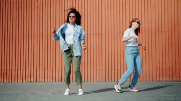 Chicas felices asiáticas y caucásicas bailando al aire libre en la calle de la ciudad divirtiéndose — Vídeos de Stock