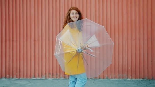 Portret całkiem Nastolatka w Płaszcz przeciwdeszczowy Spinning parasol na zewnątrz uśmiechnięty — Wideo stockowe