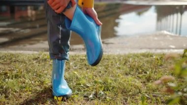 Çıplak ayakla lastik botu çıkarıp su dökmenin yakın çekim