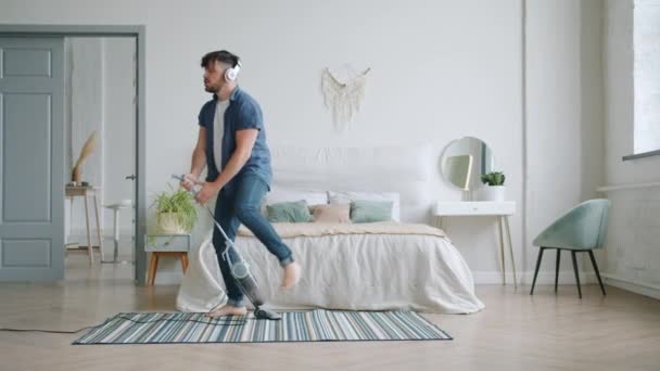 Alegre chico aspirando alfombra en casa y bailando con aspiradora — Vídeo de stock