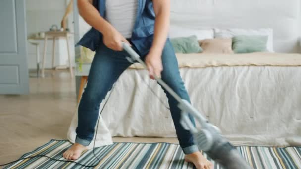 Inclinación de hombre alegre que aspira la alfombra en el apartamento fingiendo tocar la guitarra — Vídeos de Stock