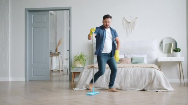 Movimiento lento del hombre en guantes de goma lavando piso y bailando con fregona de plástico — Vídeos de Stock