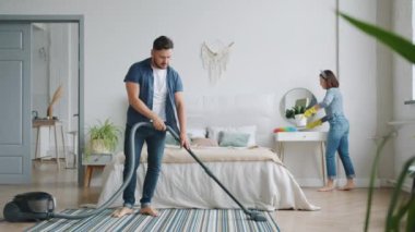 Kadın ve erkek, yatak odasının temizlik odasında elektrikli süpürgeyle ev işleriyle meşgul.