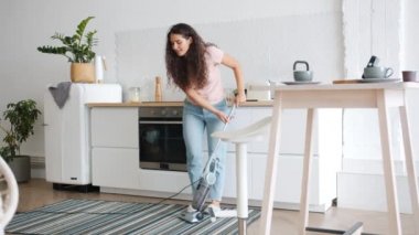 Neşeli ev hanımı mutfakta yerleri süpürüyor sonra dans ediyor, eğleniyor.