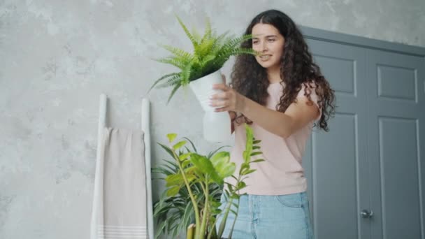 Mouvement lent de la jeune femme de chambre saupoudrant des fleurs avec de l'eau prenant soin des plantes — Video