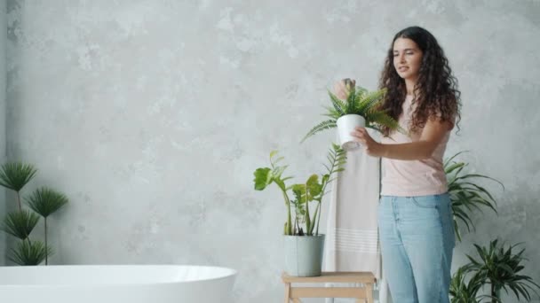 Mooie jonge dame spuiten huis planten in de badkamer met behulp van spray fles — Stockvideo