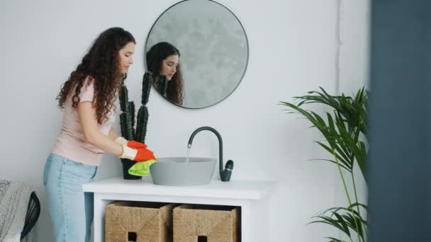 Jolie jeune femme lavabo de salle de bain avec chiffon humide portant des gants en caoutchouc — Video