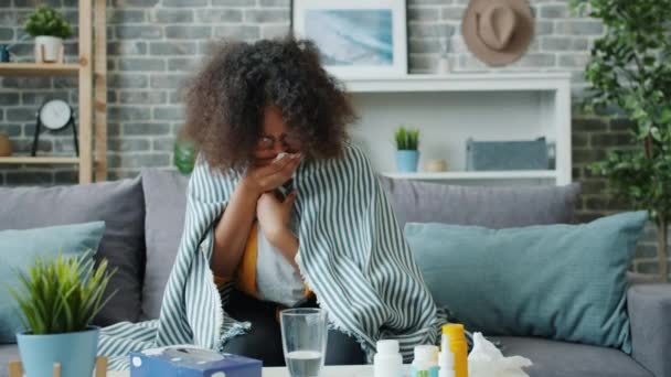 Malheureuse femme afro-américaine toussant dans du papier tissu se sentant malade à la maison — Video