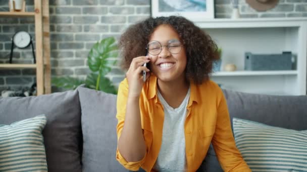 Joyful Afro-Amerikaanse tiener chatten op mobiele telefoon thuis lachen — Stockvideo