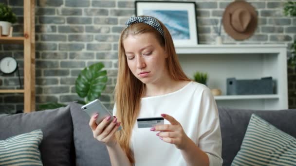 Slow motion van tiener online betalen met een bankkaart met behulp van smartphone thuis — Stockvideo