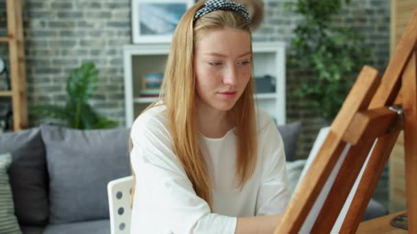 Cheerul adolescent fille peinture à la maison souriant travailler avec chevalet et crayons — Video