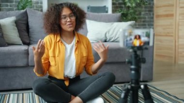 Genç Afrikalı Amerikalı kadın vlogger akıllı telefonuyla video kaydediyor.