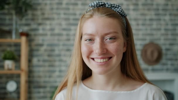 Gros plan portrait de jeune femme aux cheveux blonds regardant la caméra souriante — Video