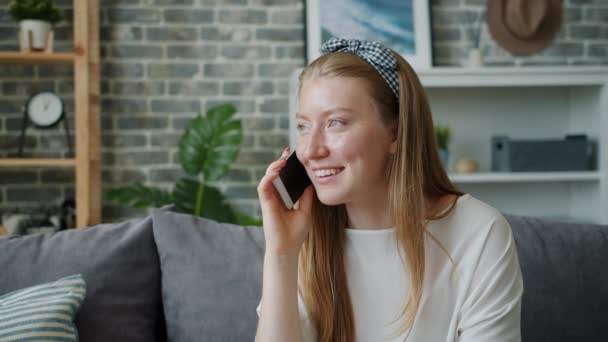 Захоплений підліток розмовляє на мобільному телефоні вдома, сміючись обговорюючи новини — стокове відео