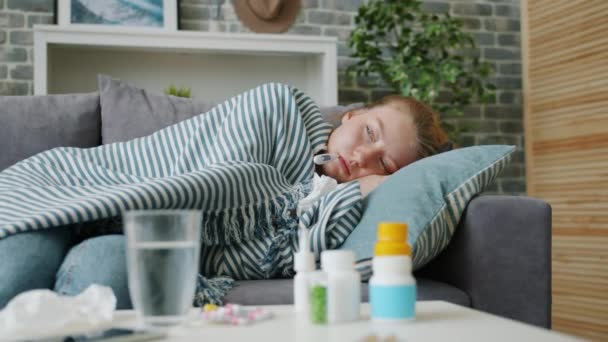 Fièvre jeune femme vérifier la température du corps couché sur le canapé à la maison — Video