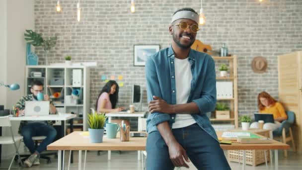 Retrato de chico afroamericano creativo en gafas divertidas sonriendo en la oficina — Vídeos de Stock