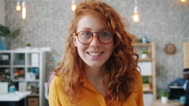 Moda gözlüklü güzel bir kadının portresi ofiste kameraya bakıp gülümsüyor.