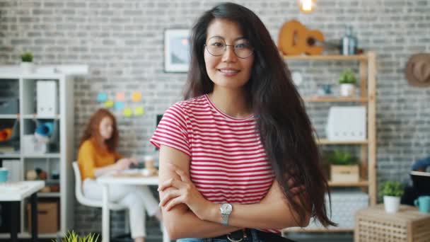 Cámara lenta de la mujer de negocios asiática de pie en la oficina con los brazos cruzados sonriendo — Vídeos de Stock