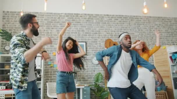 Movimiento lento de jóvenes alegres equipo multiétnico bailando en la oficina aplaudiendo de la mano — Vídeos de Stock