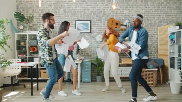 Wielorasowa grupa pracowników biurowych tańczy rzucając dokumentami śmiejąc się — Wideo stockowe