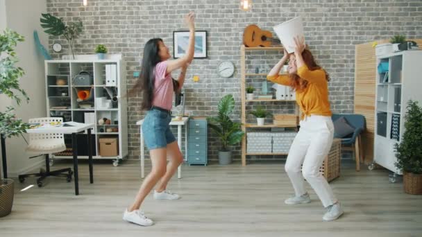 Feliz jóvenes trabajadoras de oficina divirtiéndose en el trabajo tirando papel en la papelera — Vídeos de Stock