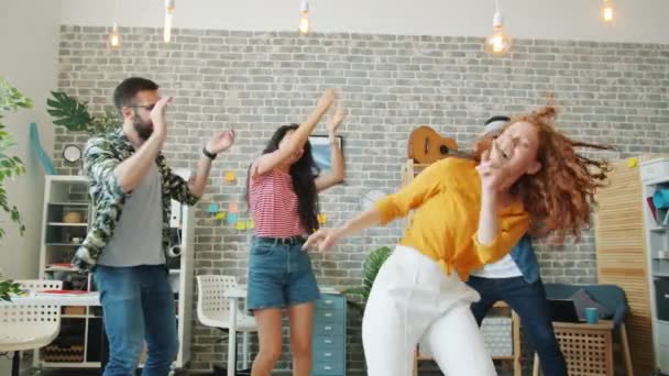 Рыжая девушка танцует на корпоративной вечеринке, а коллеги хлопают в ладоши, смеясь — стоковое видео