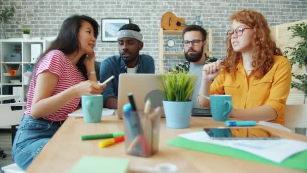 Multi-ethnic group discussing business laughing looking at laptop in office — ストック動画