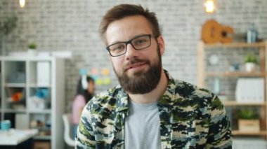 Ofiste durup kameraya gülümseyen iş adamının portresi.