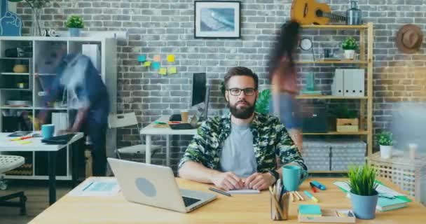 Time lapse portret van goed uitziende jonge man op zoek naar camera in het kantoor — Stockvideo