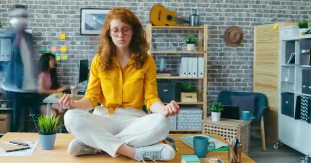 Time lapse of tired office worker relaxing sitting on desk in lotus position — Stock Video