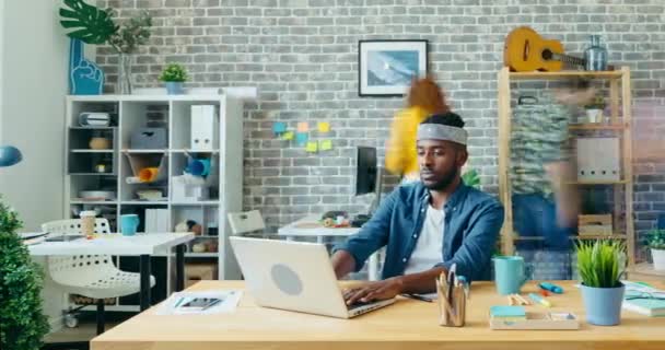 Время красивого афро-американского хипстера, использующего ноутбук в современном офисе — стоковое видео