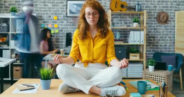 Lapso de tempo de mulher ruiva bonita relaxando no escritório na posição de lótus — Vídeo de Stock