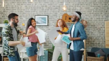 Çok ırklı takım ofiste dans ediyor. İş sözleşmeleri fırlatıp gülüyor.