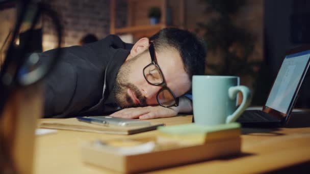 Уставший менеджер спит на столе в офисе по ночам, пока коллеги работают — стоковое видео