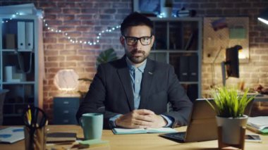 Akşamları ofiste kameraya bakan ciddi bir girişimcinin portresi