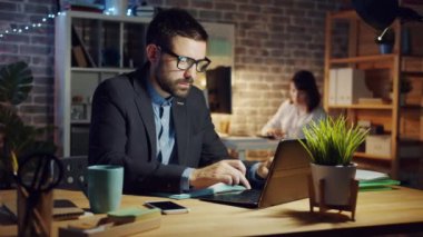 Yakışıklı iş adamı laptopta iyi haberler alıyor. Akşam ofiste çalışıyor.