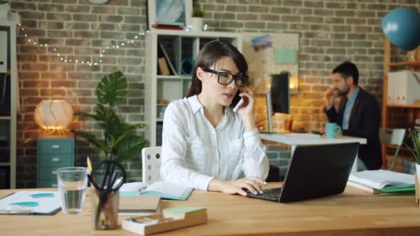 Belle employée de bureau bavardant sur un téléphone portable dans le bureau souriant — Video