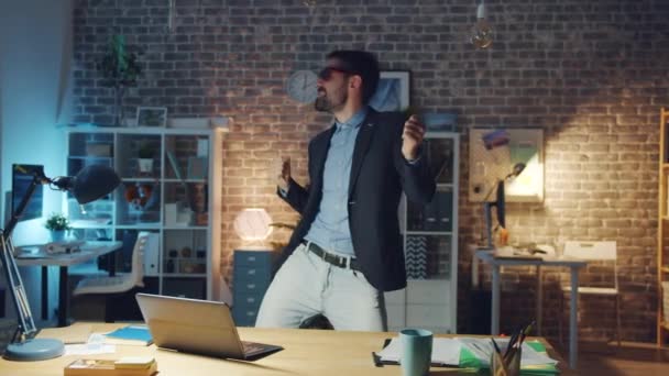 Pen kontorarbeider med stilige briller som danser på kontorrommet om kvelden – stockvideo