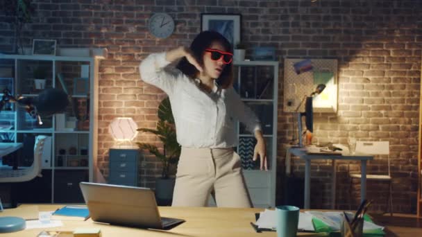 Piękna kobieta w śmiesznych okularach relaksująca się w biurze w nocy tańcząca zabawiając się — Wideo stockowe