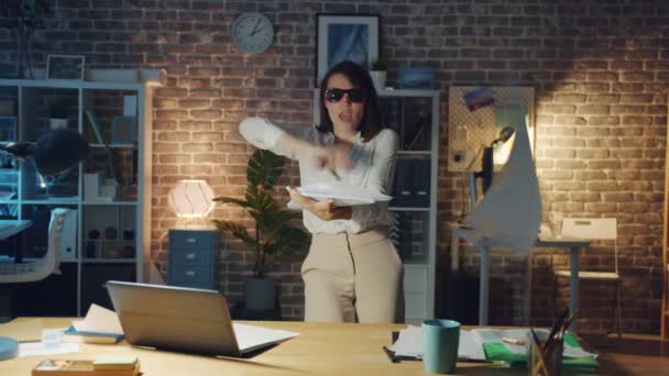 Niedliche Geschäftsfrau, die nachts im Büro tanzt und Papiere wirft, die Spaß machen — Stockvideo