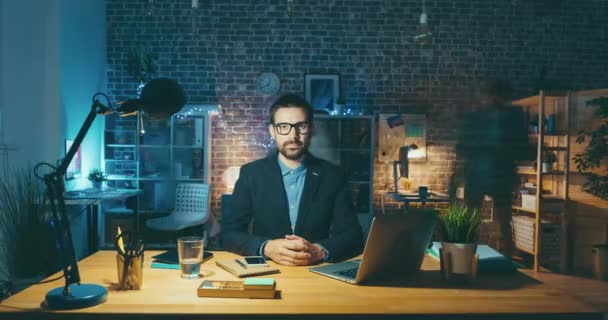 Time lapse portrait of handsome man sitting at desk in office looking at camera — ストック動画