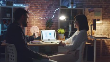 Akıllı telefon uygulaması arayüzünü tartışan yaratıcı insanlar ofiste dizüstü bilgisayarla çalışıyorlar