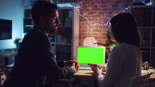 Деловые люди разговаривают в офисе глядя на экран ноутбука хрома ключ ночью — стоковое видео